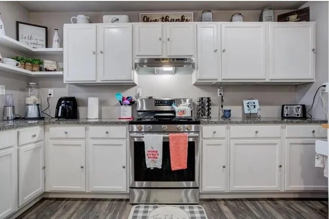 a kitchen with stainless steel appliances granite countertop white cabinets sink and stove