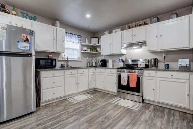 a kitchen with stainless steel appliances white cabinets a sink a stove a refrigerator and white cabinets