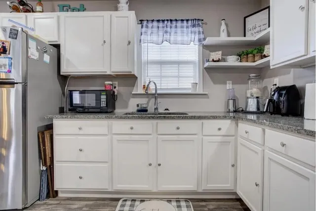 a kitchen with granite countertop white cabinets and white appliances