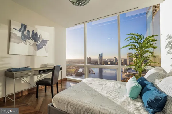 a bedroom with a bed table chair and a potted plant