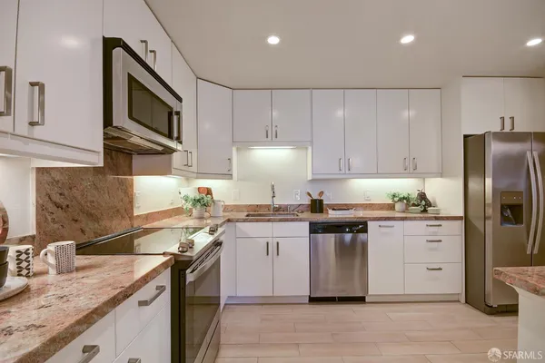 a kitchen with stainless steel appliances granite countertop a sink and dishwasher with white cabinets