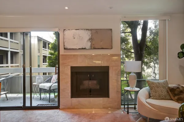a living room with furniture a fireplace and a floor to ceiling window