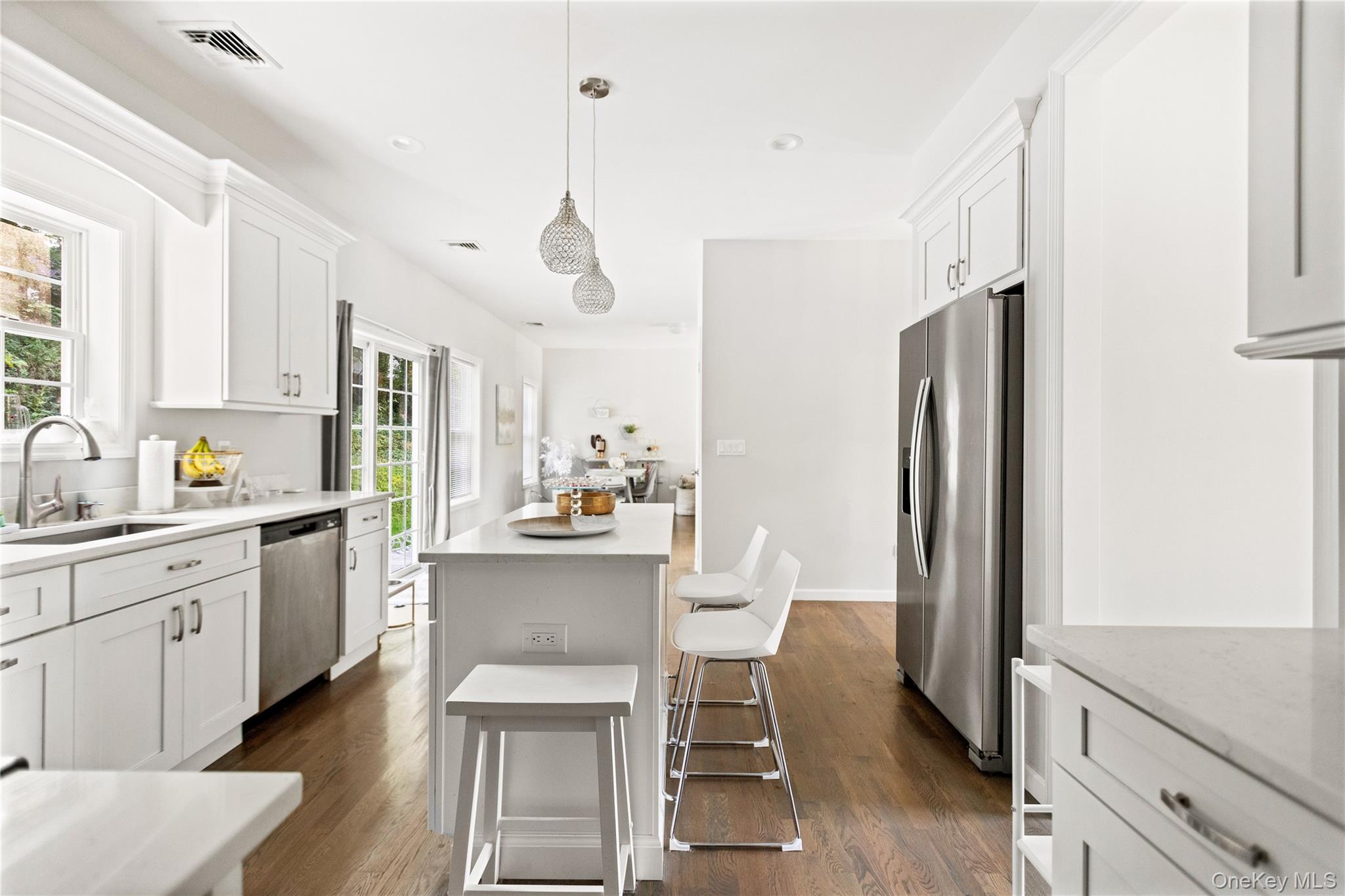 24 Belmont Road Sound Beach, NY 11789 - Photo 6 of 23 a kitchen with stainless steel appliances a dining table chairs refrigerator and sink