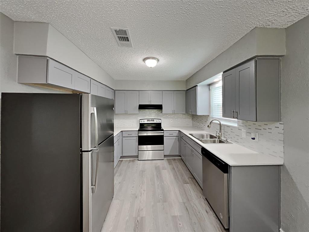 702 Redbud Drive Forney, TX 75126 - Photo 9 of 16 a large kitchen with a center island wooden floor and stainless steel appliances