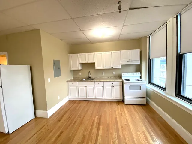 a kitchen with stainless steel appliances a refrigerator a sink dishwasher a stove and white cabinets with wooden floor