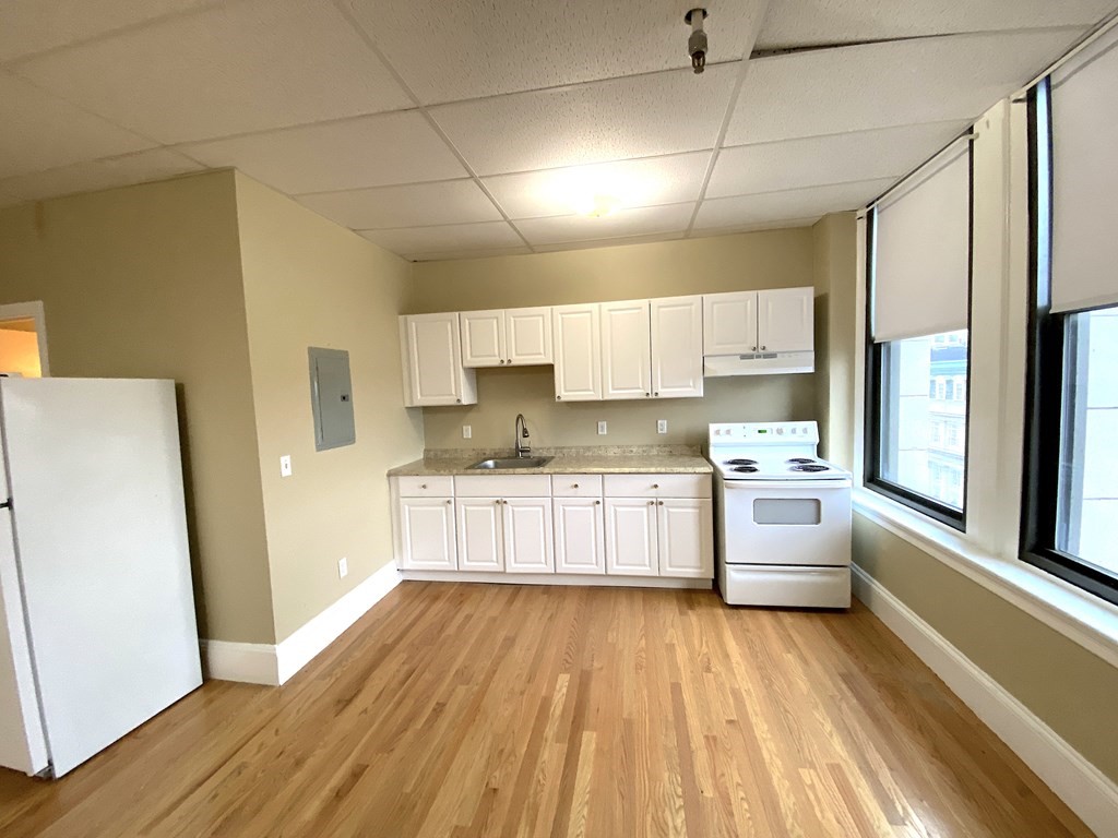 11 Lawrence Street, Unit 606 Lawrence, MA 01840 - Photo 3 of 10 a kitchen with stainless steel appliances a refrigerator a sink dishwasher a stove and white cabinets with wooden floor