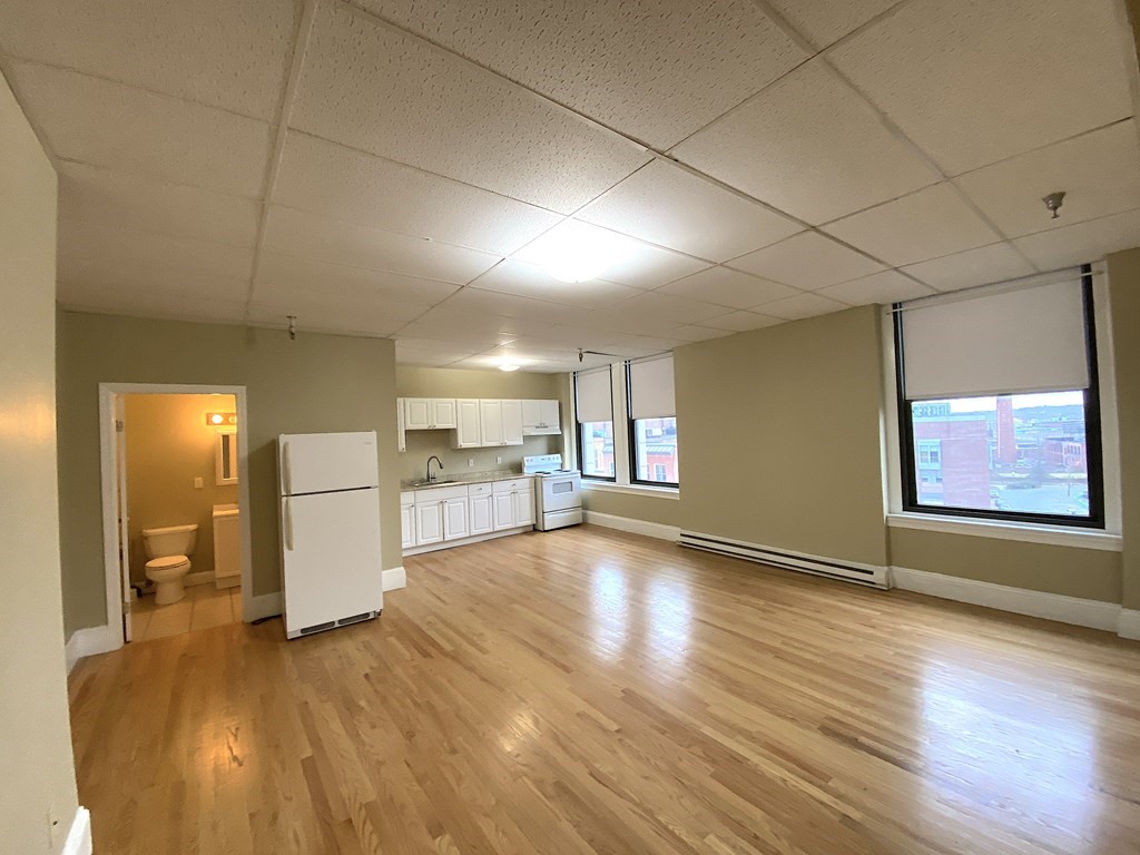 11 Lawrence Street, Unit 606 Lawrence, MA 01840 - Photo 7 of 10 a view of an empty room with wooden floor and a kitchen