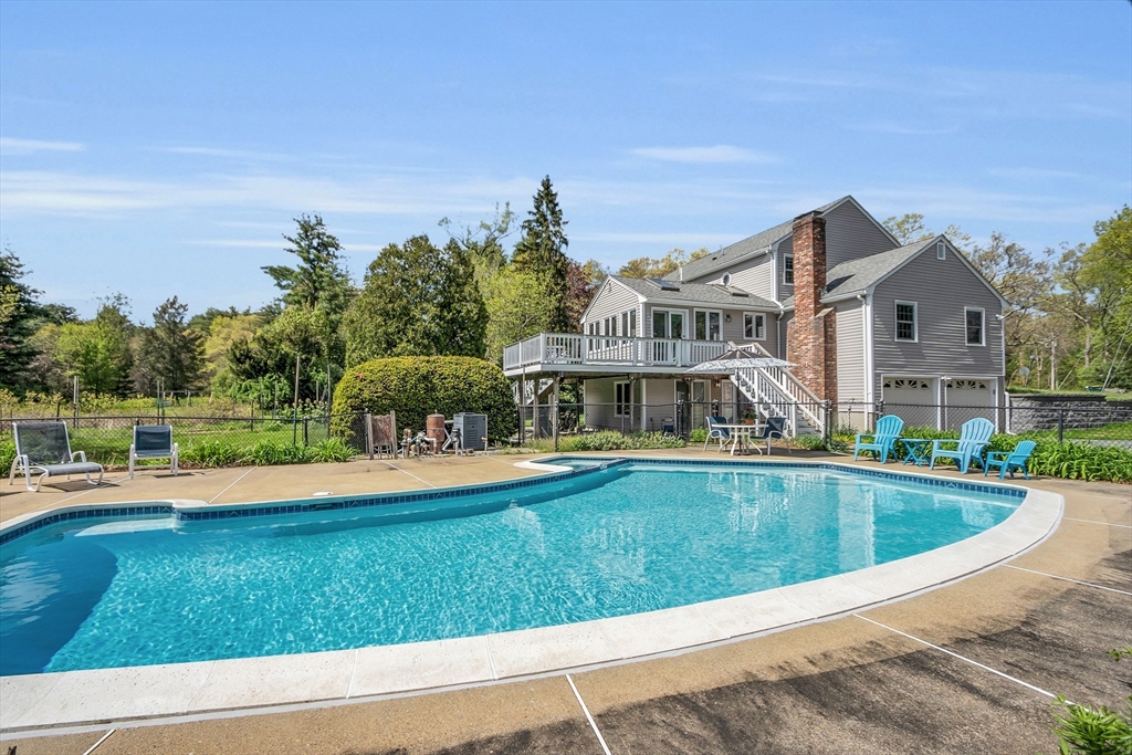 a view of swimming pool with lawn chairs and plants