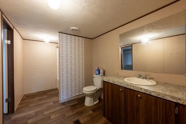 a bathroom with a granite countertop sink a toilet a mirror and shower curtain