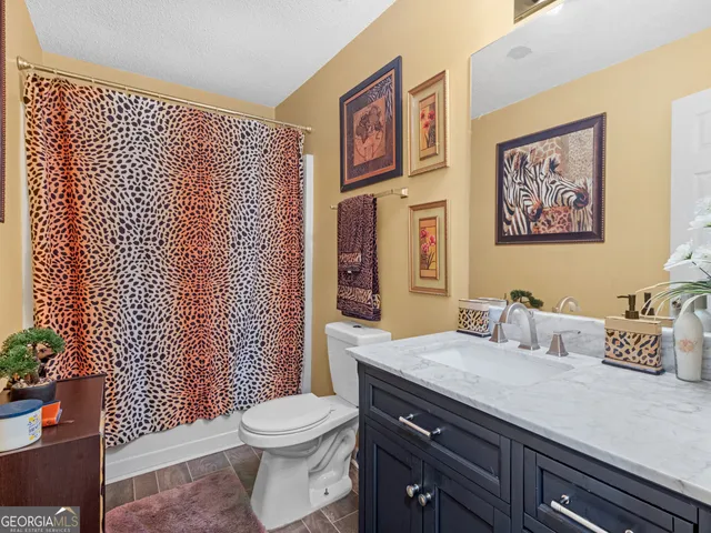a bathroom with a granite countertop toilet sink and mirror
