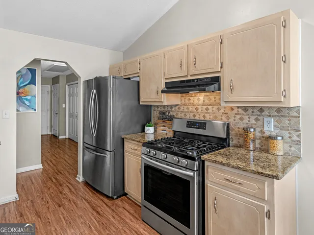 a kitchen with granite countertop a stove sink and refrigerator