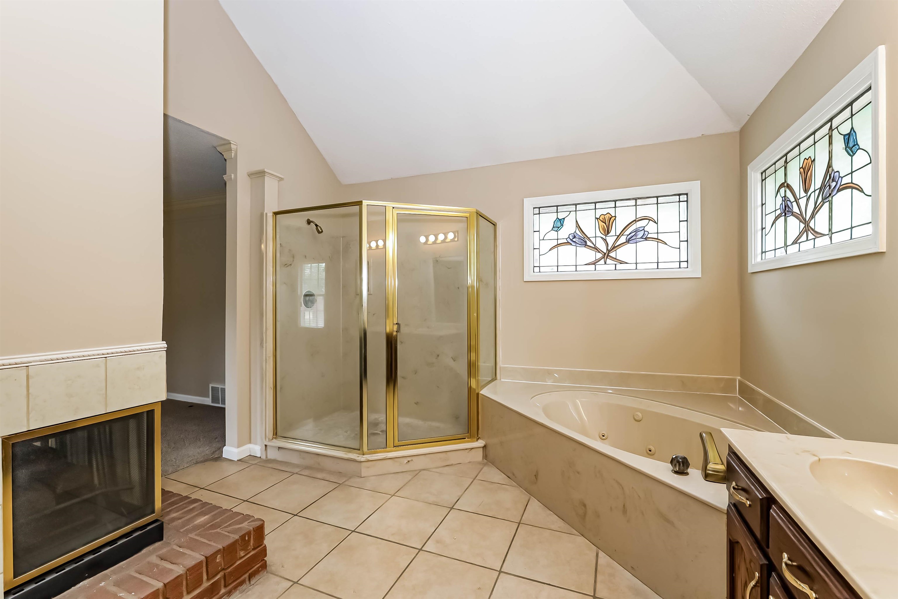 432 Leaf Trail Lane Memphis, TN 38018 - Photo 12 of 17 Bathroom featuring tile patterned flooring, lofted ceiling, vanity, a brick fireplace, and plus walk in shower