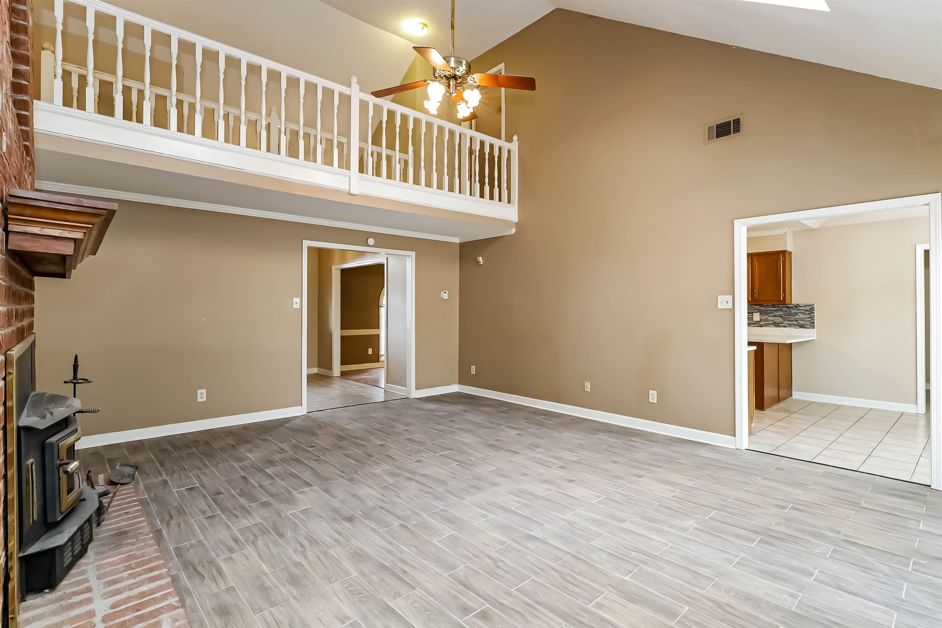 432 Leaf Trail Lane Memphis, TN 38018 - Photo 4 of 17 Unfurnished living room featuring high vaulted ceiling, light wood-type flooring, ceiling fan, and a wood stove