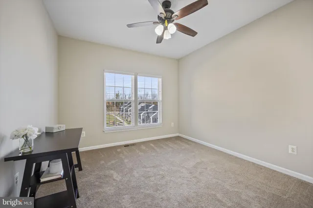 a view of an empty room and chandelier fan