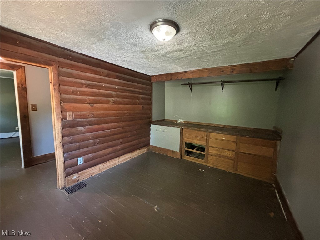 5164 Rutledge Street Southeast Dennison, OH 44621 - Photo 8 of 14 Empty room with rustic walls, a textured ceiling, and dark hardwood / wood-style floors