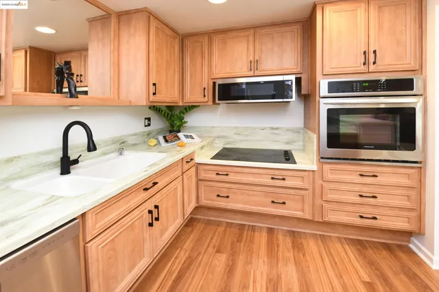 a kitchen with granite countertop white cabinets stainless steel appliances and a sink
