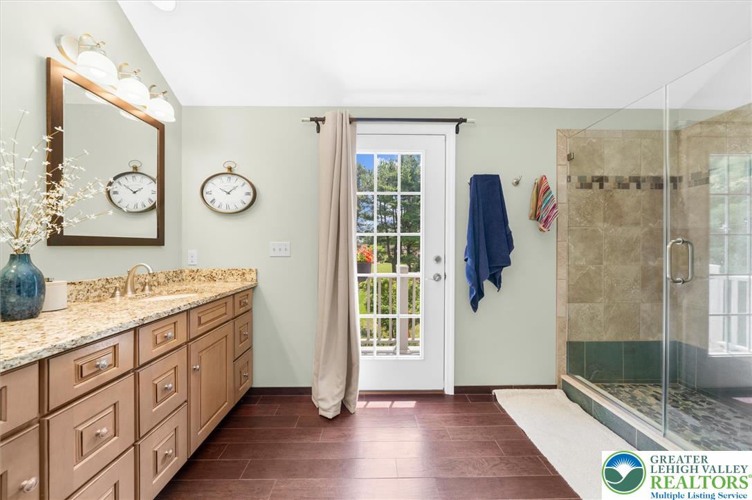 5616 Snowdrift Road Orefield, PA 18069 - Photo 15 of 36 This primary bathroom features a double vanity with granite counters, a glass-enclosed shower, and a private balcony entrance.