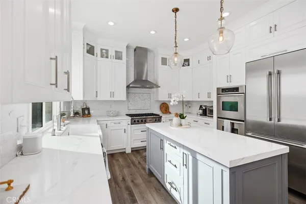 a kitchen with a stove a sink a kitchen island with wooden cabinets and stainless steel appliances
