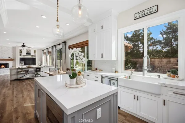 a kitchen with a sink a counter top space and living room view