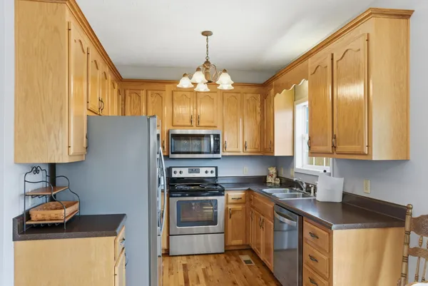 a kitchen with stainless steel appliances granite countertop a refrigerator a stove top oven a sink dishwasher and wooden floor