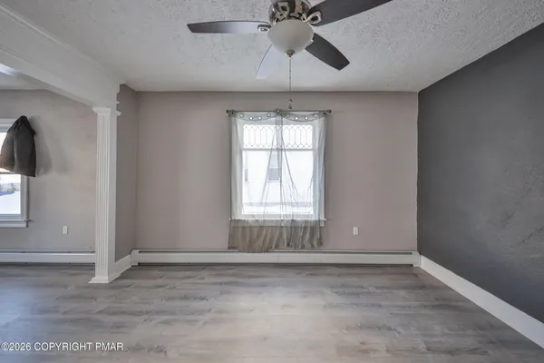 an empty room with windows and chandelier fan