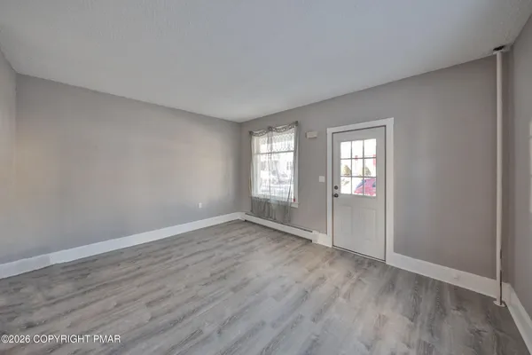 an empty room with wooden floor and windows