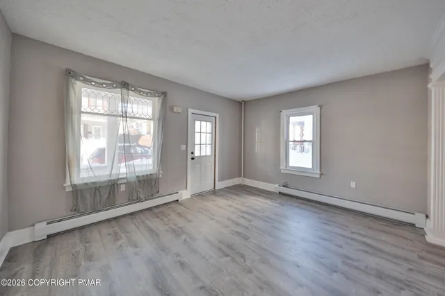 a view of an empty room with wooden floor and a window