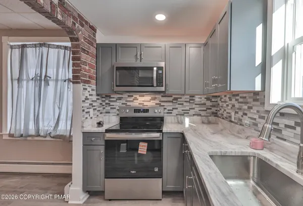 a kitchen with granite countertop a sink stove and microwave
