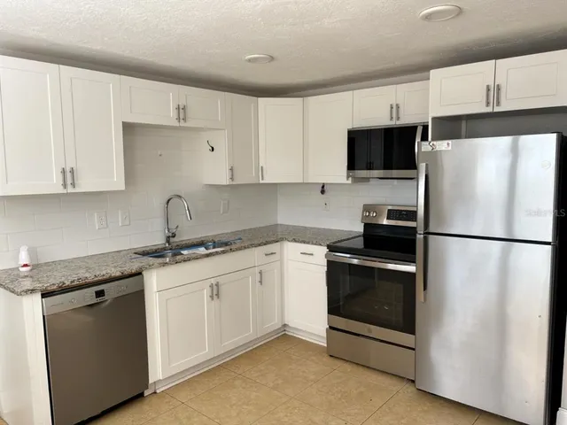 a kitchen with stainless steel appliances granite countertop a refrigerator sink and white cabinets