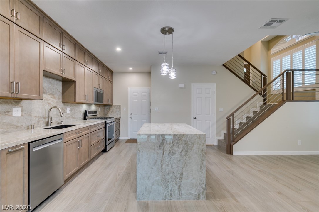 540 Sutters Mill Road Henderson, NV 89014 - Photo 24 of 46 This open concept kitchen features sleek cabinetry, modern appliances, and a captivating waterfall island, seamlessly connecting to a stylish staircase.