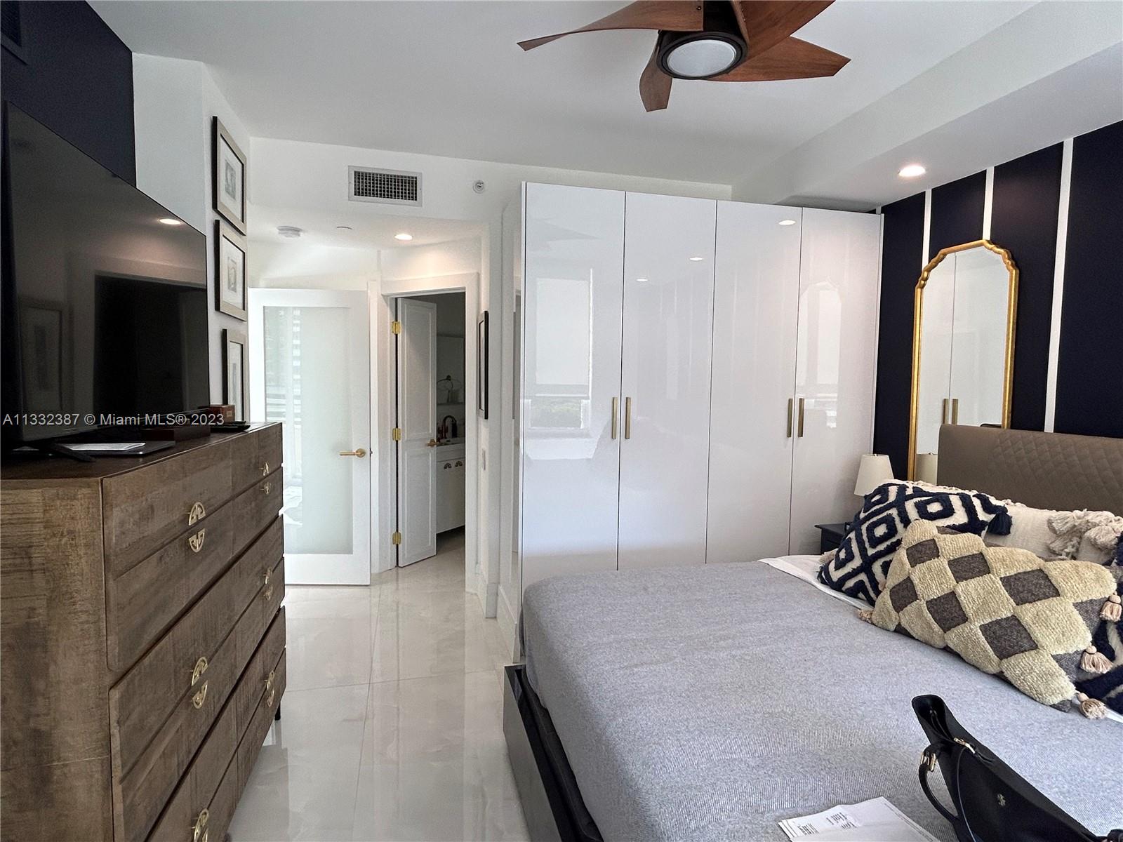 888 Brickell Key Drive, Unit 802 Miami, FL 33131 - Photo 11 of 42 a bedroom with a bed and a flat tv screen on dresser