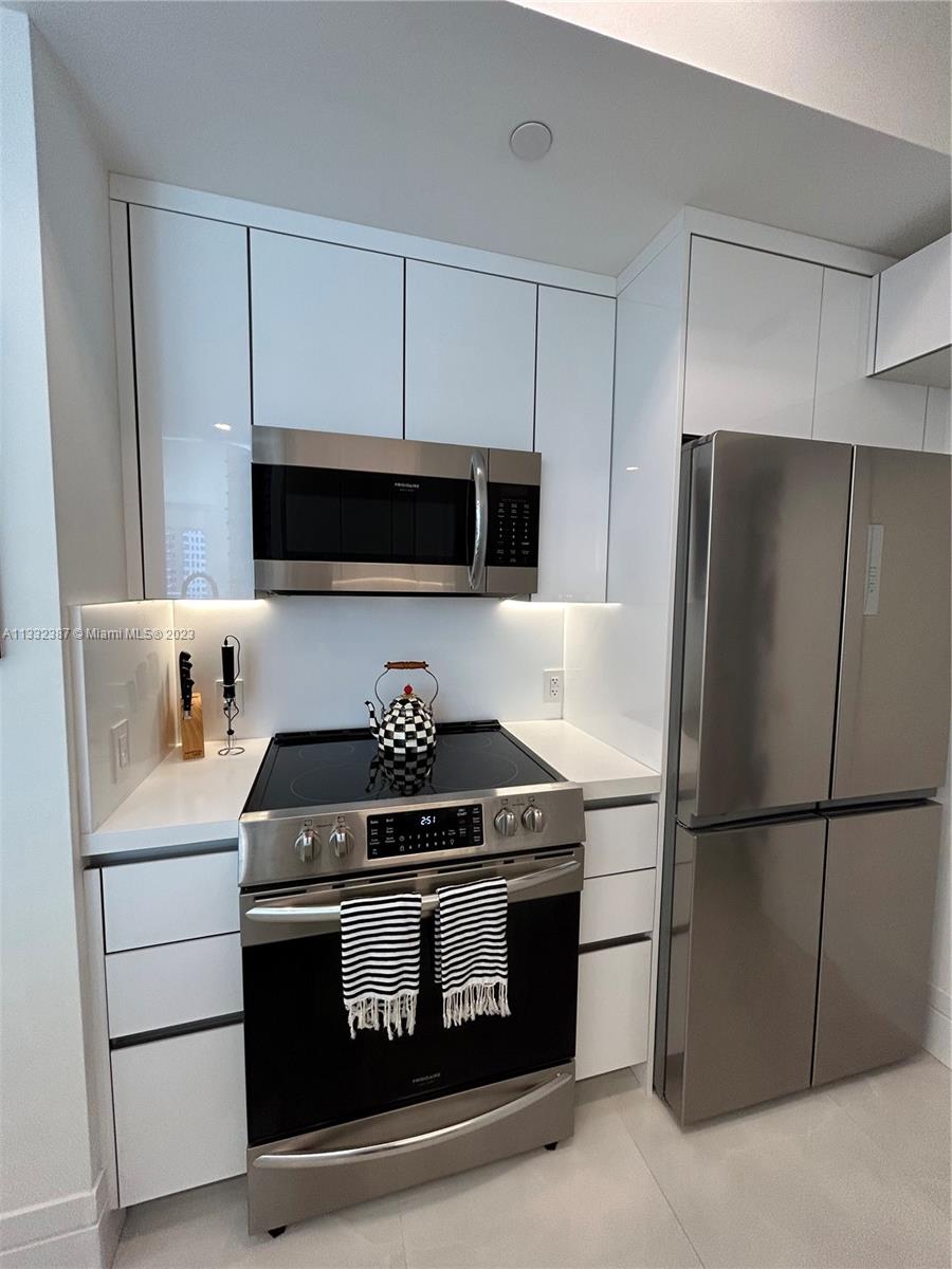 888 Brickell Key Drive, Unit 802 Miami, FL 33131 - Photo 35 of 42 a kitchen with stainless steel appliances granite countertop a stove and a refrigerator with white cabinets
