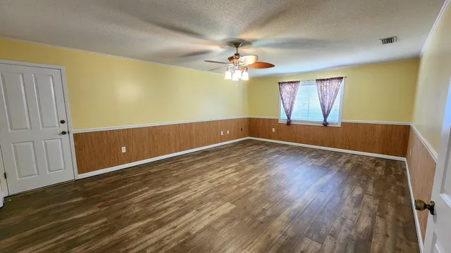 a view of an empty room with wooden floor and chandelier