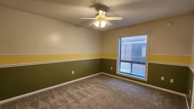 an empty room with a ceiling fan and a window