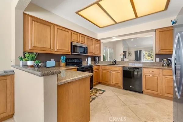 a kitchen with stainless steel appliances granite countertop a stove top oven a sink dishwasher and a refrigerator with wooden floor