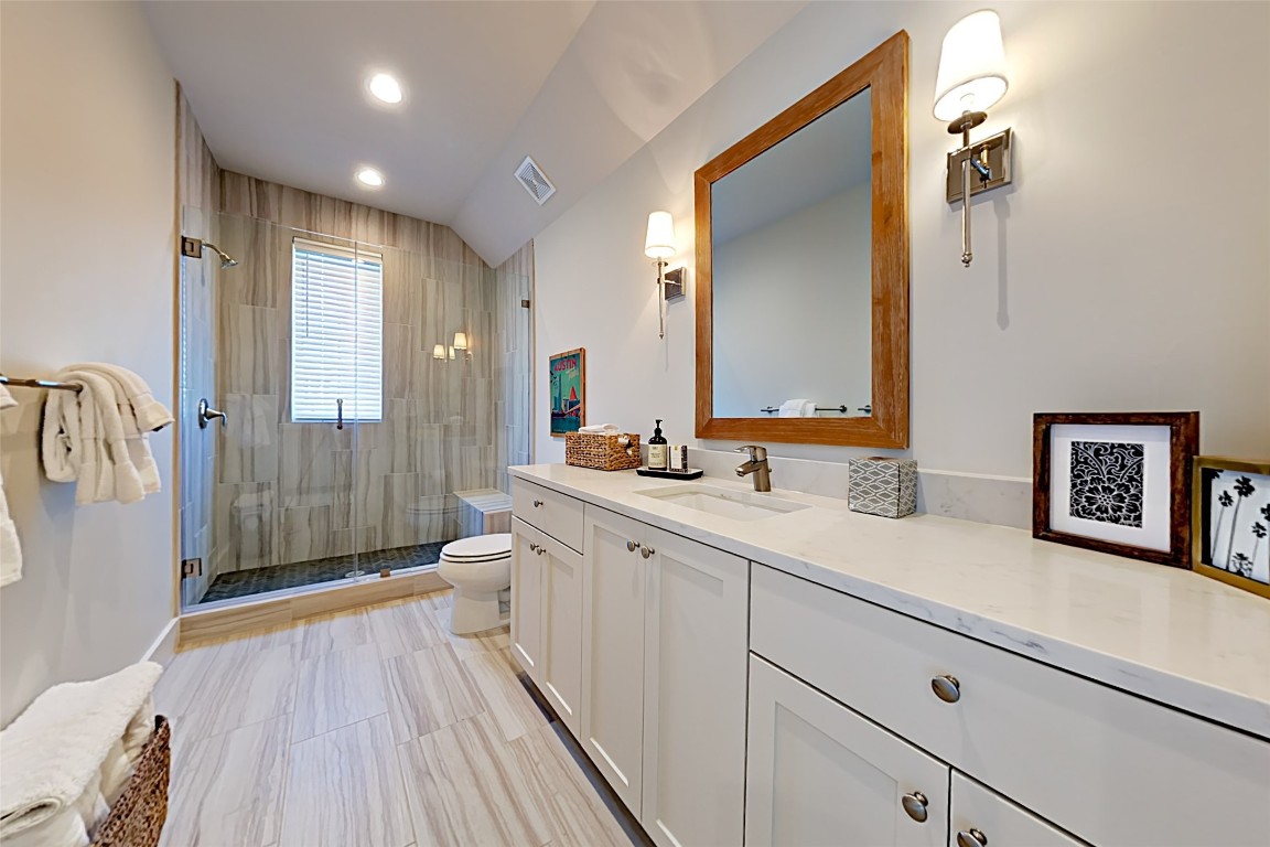 19517 Flying J Boulevard, Unit 6 Spicewood, TX 78669 - Photo 28 of 32 a spacious bathroom with a double vanity sink a large mirror and shower