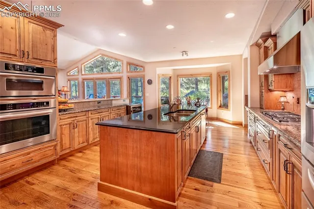 a kitchen with stainless steel appliances granite countertop a stove a sink and a refrigerator