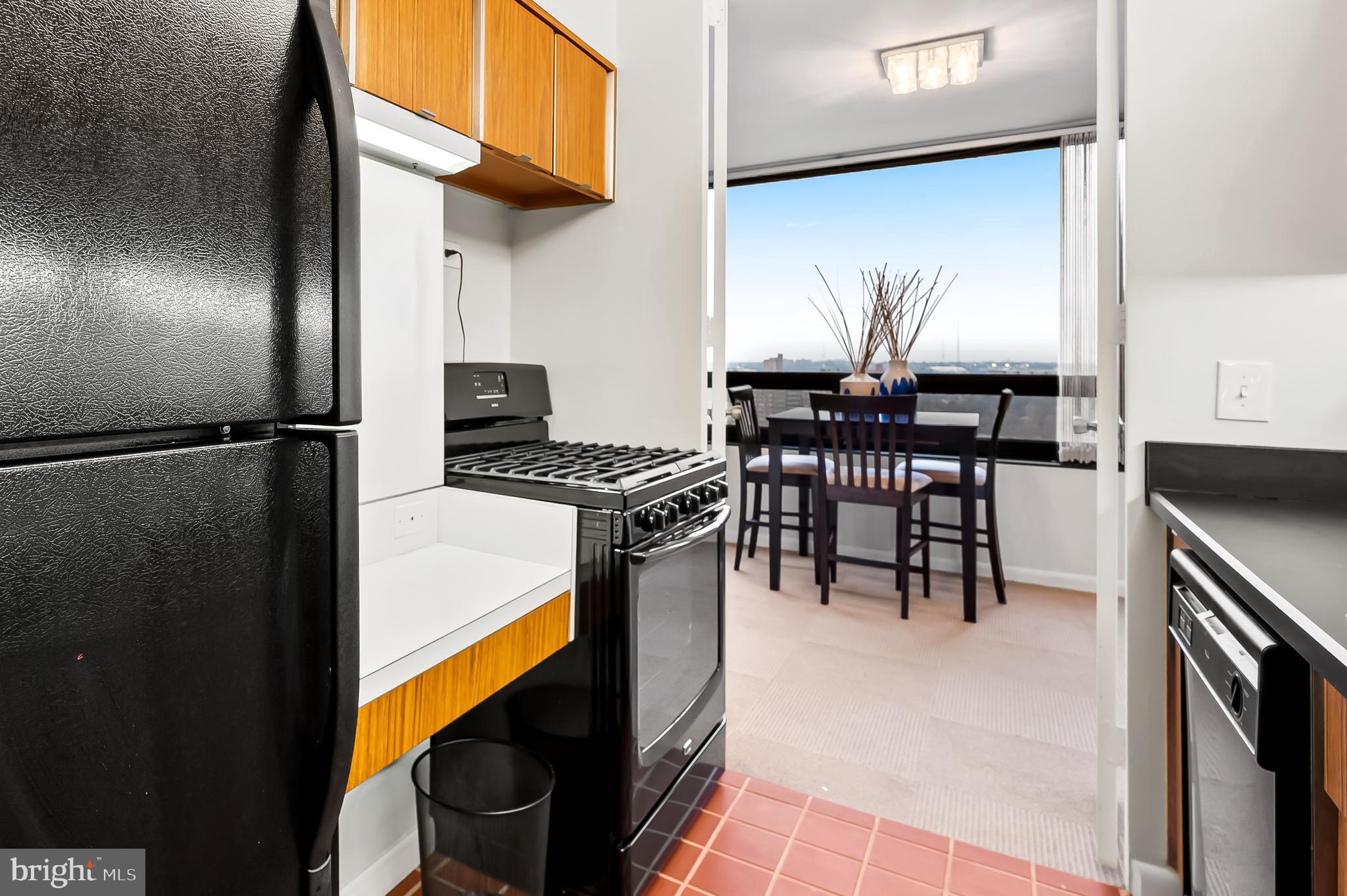 4000 North Charles Street, Unit 1605 Baltimore, MD 21218 - Photo 17 of 45 a kitchen with stainless steel appliances granite countertop a stove a refrigerator and a dining table