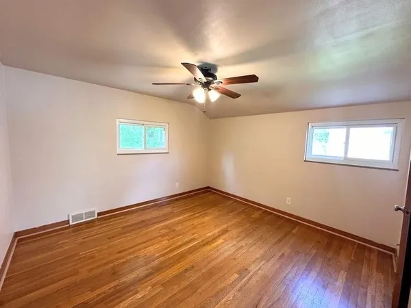 a view of an empty room with a window and wooden floor