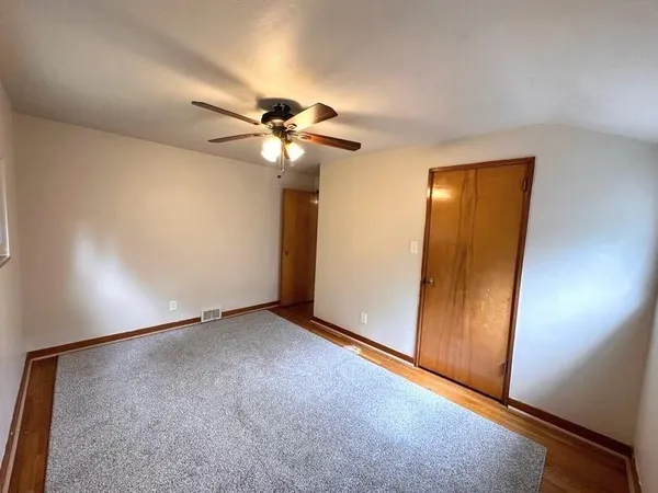 an empty room with closet and a chandelier fan