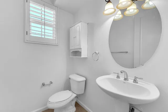 a bathroom with a sink a mirror a toilet and a window