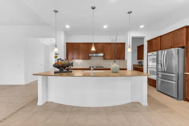 a large kitchen with kitchen island a large counter top stainless steel appliances and cabinets