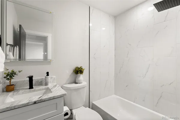 a bathroom with a granite countertop sink mirror vanity and toilet
