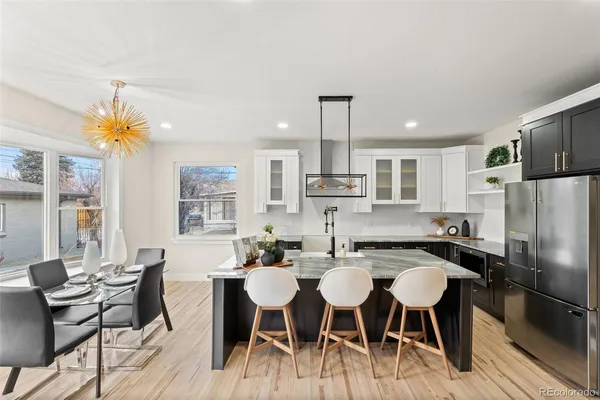 a kitchen with stainless steel appliances a dining table chairs and a refrigerator