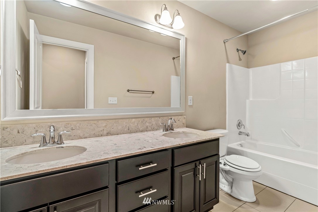 3917 174th Place Southeast Bothell, WA 98012 - Photo 23 of 31 a bathroom with a granite countertop sink toilet a large mirror a bathtub and shower