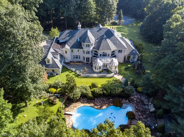 a aerial view of a house with swimming pool a yard and a fountain