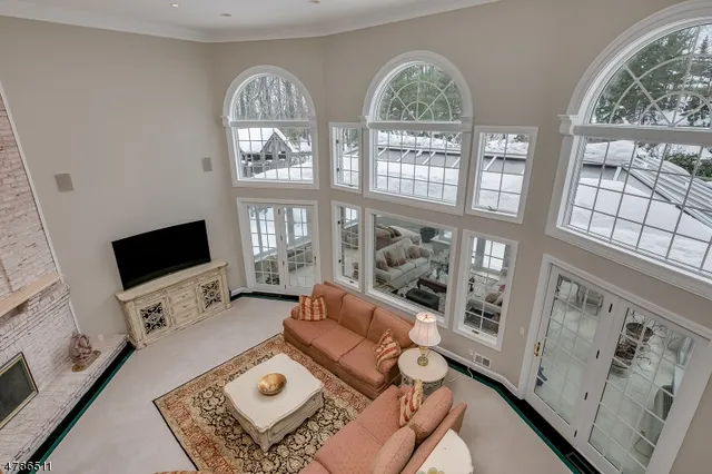 a living room with furniture a floor to ceiling window and a flat screen tv