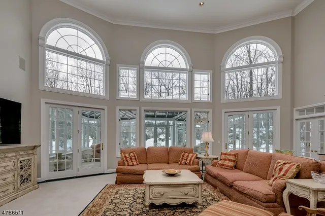 a living room with furniture two large windows and a flat screen tv