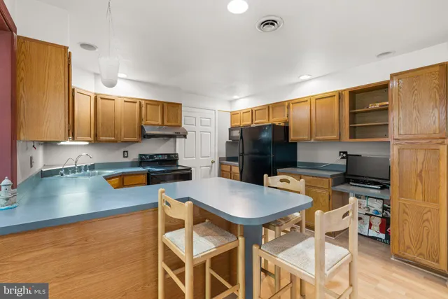 a kitchen with stainless steel appliances granite countertop a refrigerator a stove top oven a sink dishwasher and white cabinets with wooden floor