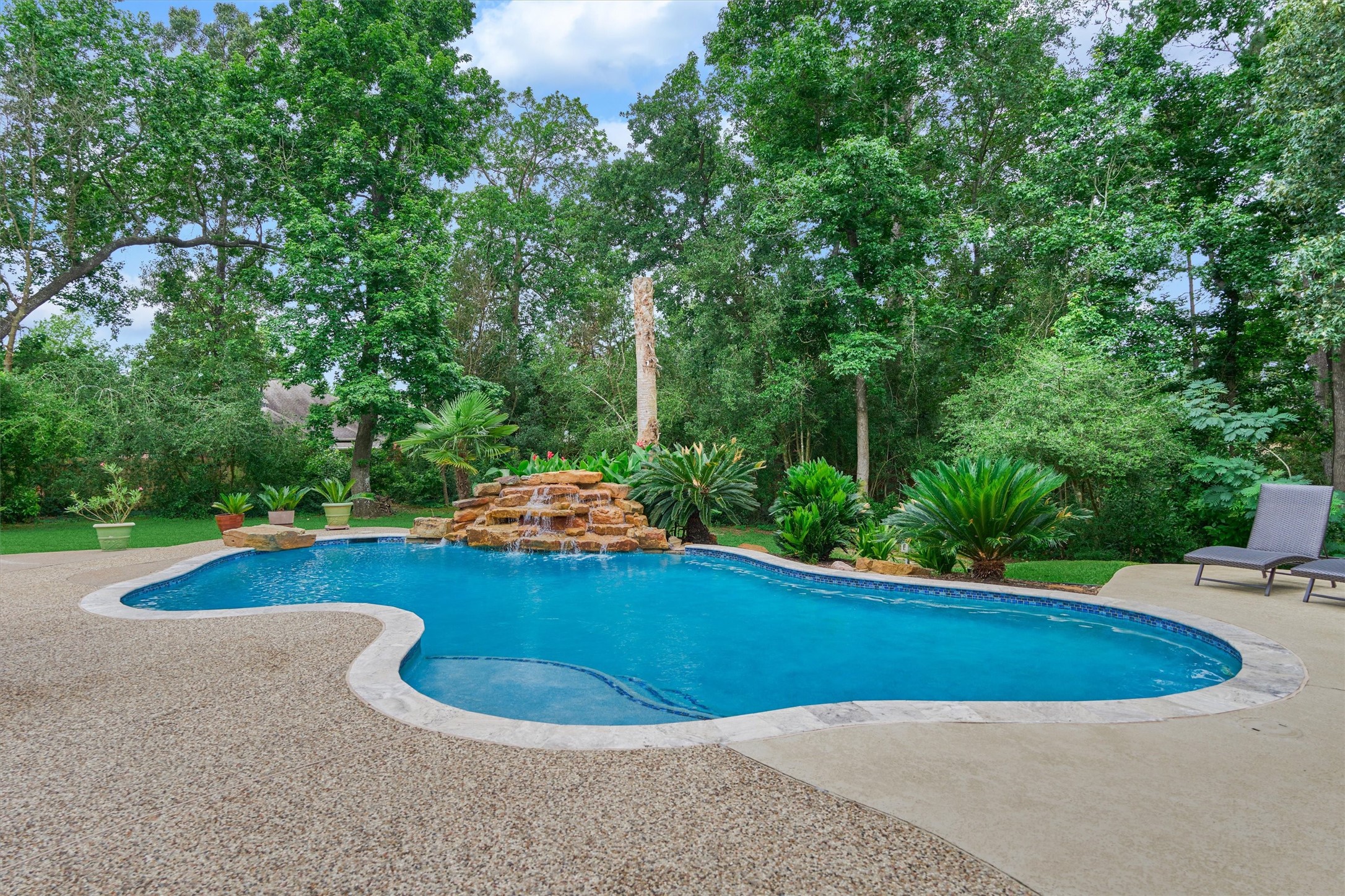 2500 Eagle Post Drive Conroe, TX 77304 - Photo 39 of 50 Stunning pool with waterfall feature and jumping rock is surrounded by tall, mature trees and multiple venues to relax and enjoy!
